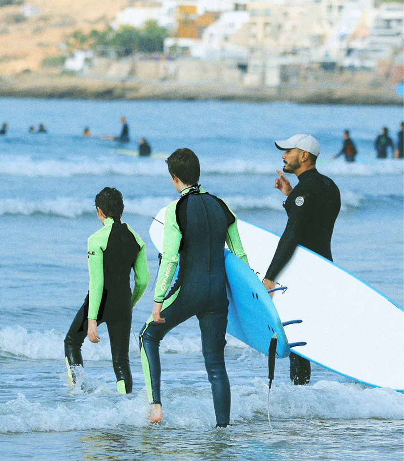 Hatim donnant un briefing de sécurité à deux adolescents avant un cours de surf en famille